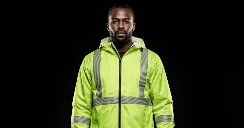 A man wearing a pair of dark-colored pants and a yellow high-visibility jacket with reflective striping.