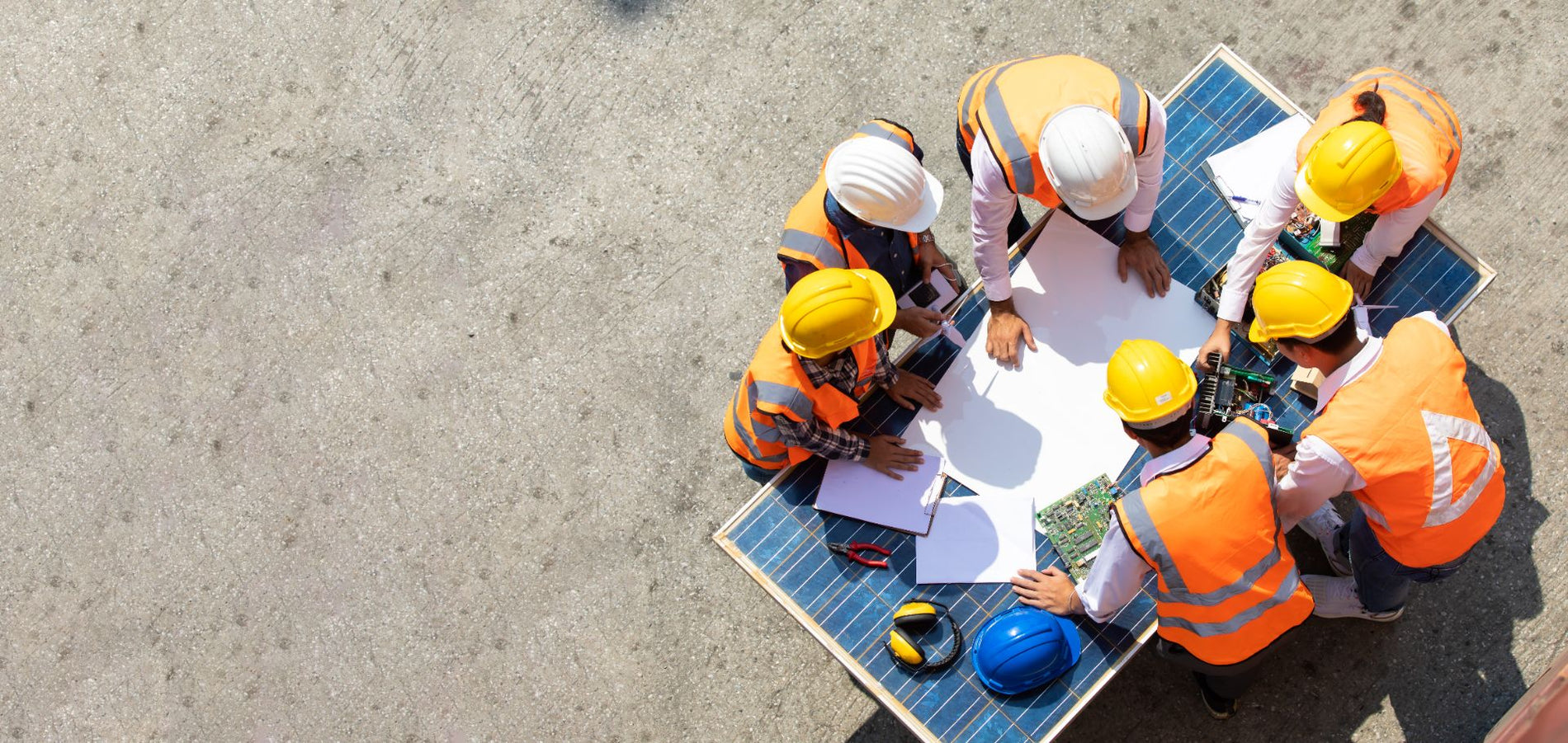 A diverse group of workers, including men and women of different ethnic backgrounds, wearing safety helmets