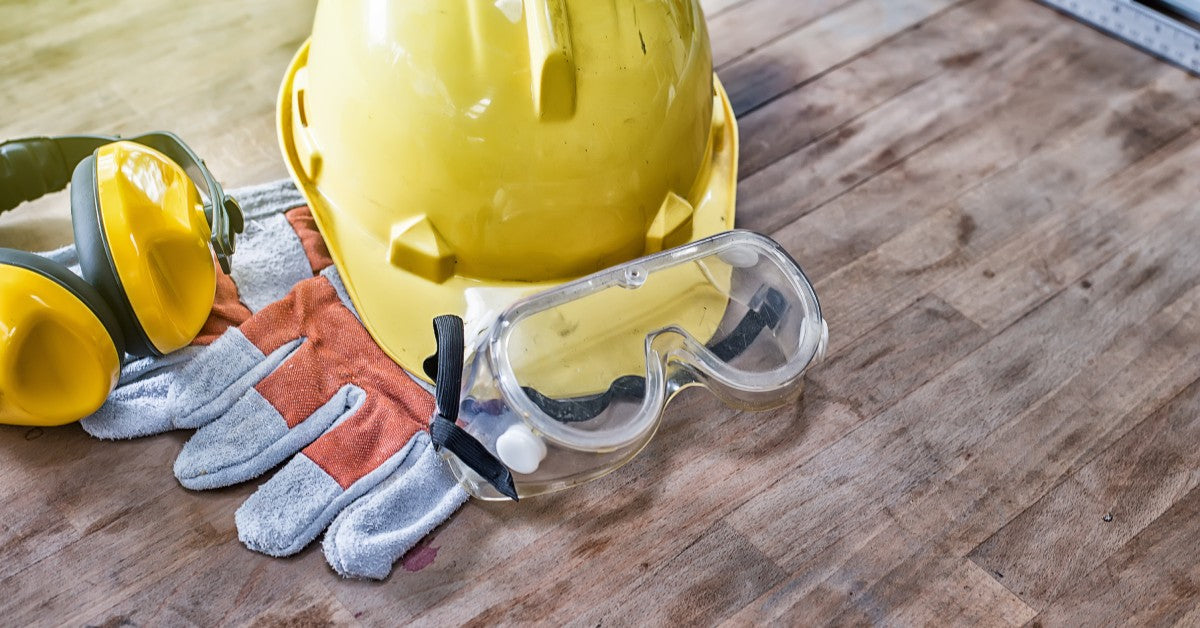 A selection of standard construction safety equipment spread out on a wooden table, viewed from above.